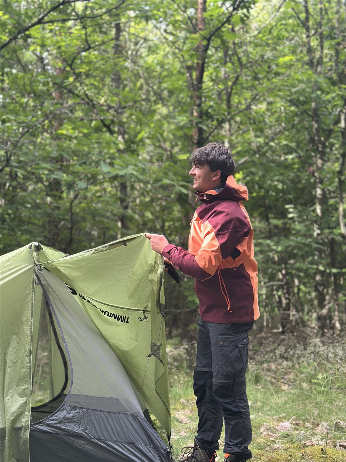 Produkttester trägt die Ternua Klimmer Jacket beim Zeltaufbau im Wald