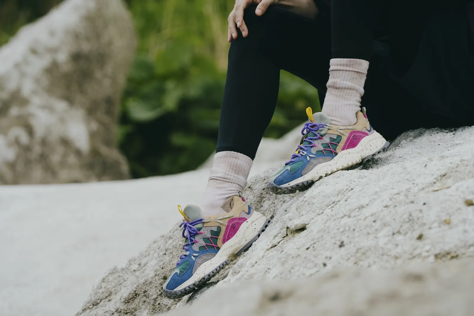Füße in bunten Flower-Mountain-Sneakern auf einem Felsen
