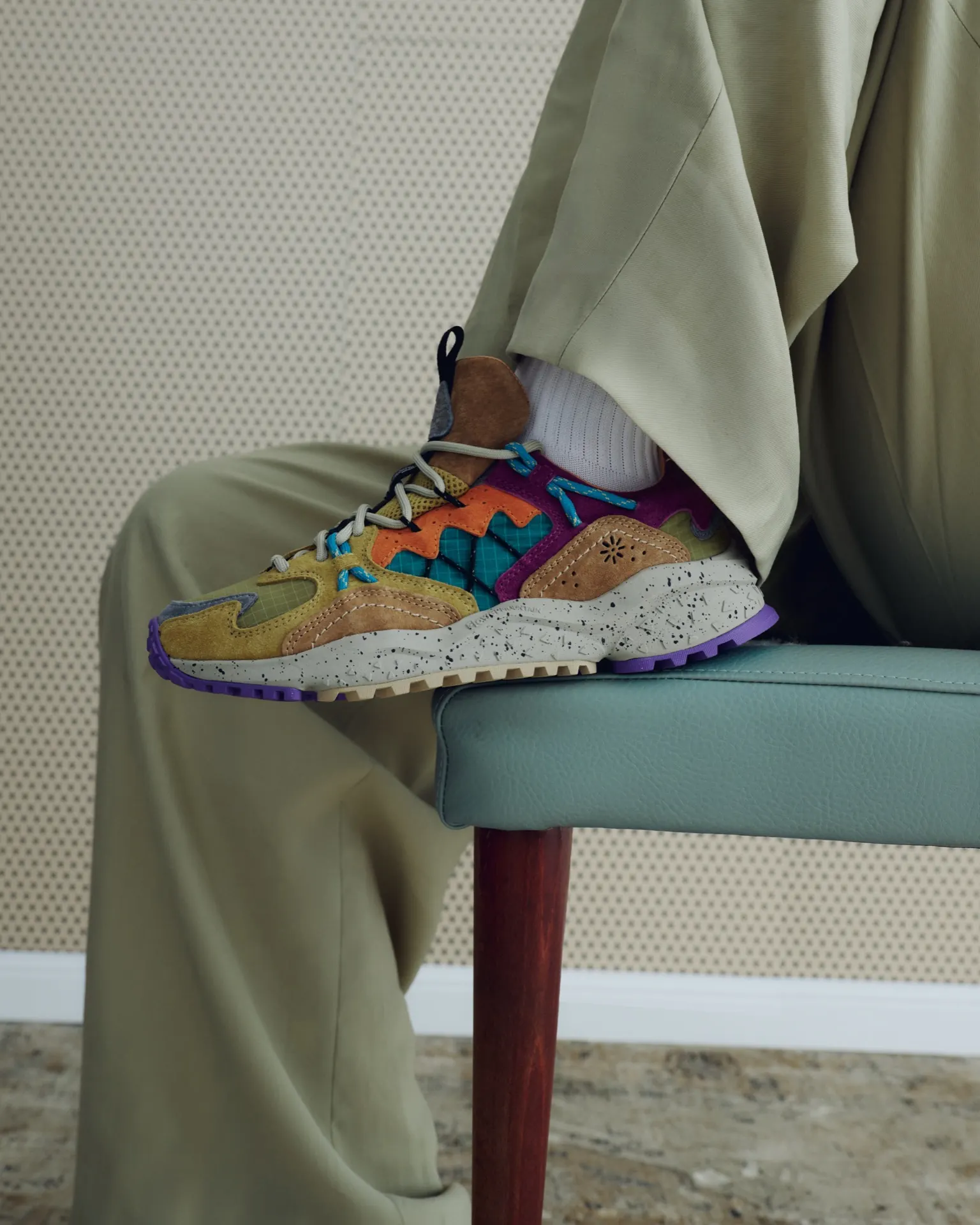 Orange-bunte Flower-Mountain-Sneaker an einem Stuhlbein