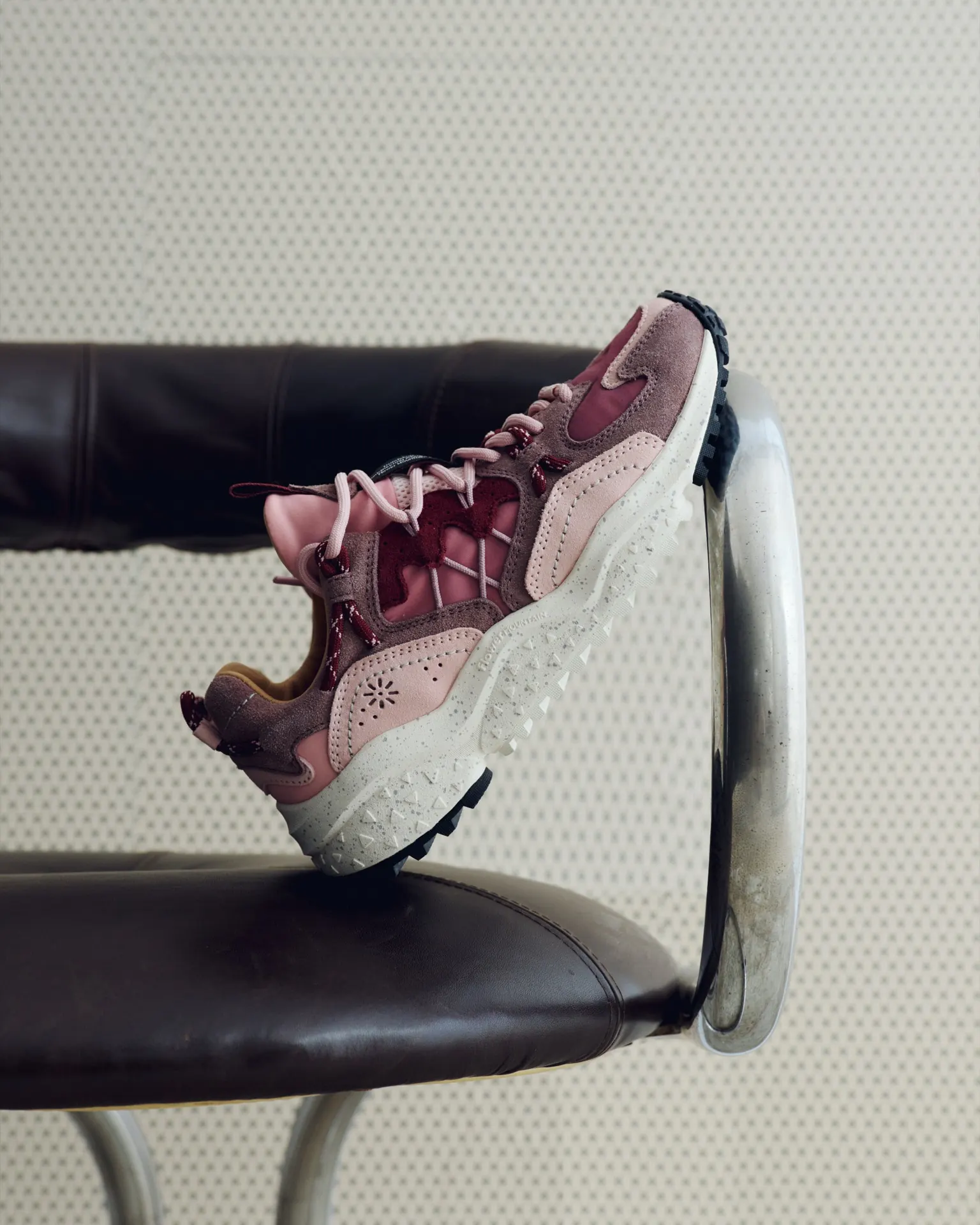 Rosa-grauer Flower-Mountain-Sneaker auf einer Stuhllehne