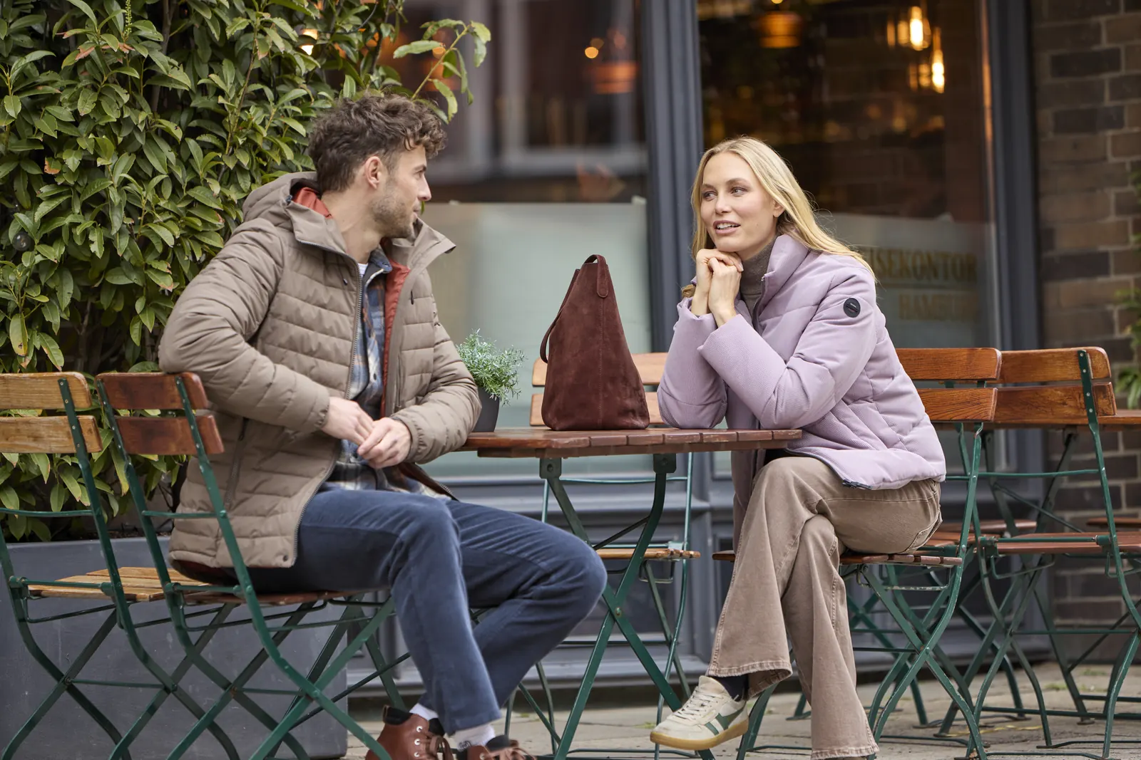 Paar in Winterjacken von G.I.G.A. DX sitzt vor einem Café