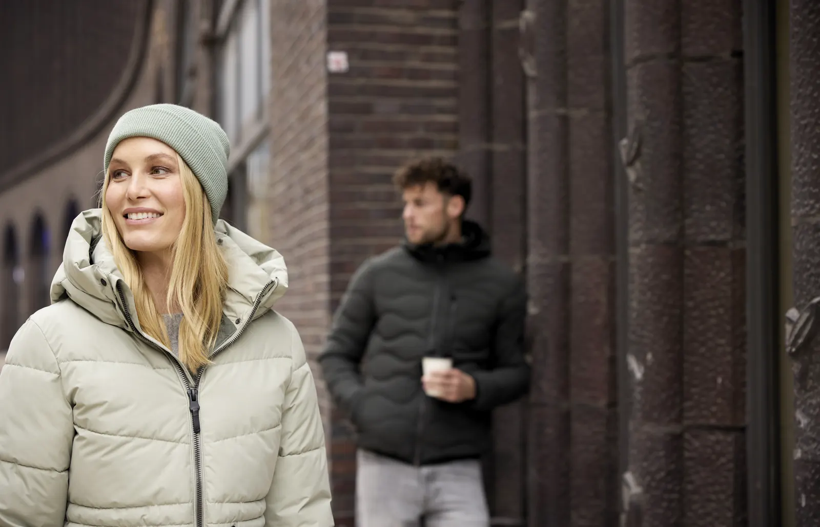 Frau mit heller Steppjacke und Mann mit dunkler Jacke auf einer Straße in der Stadt
