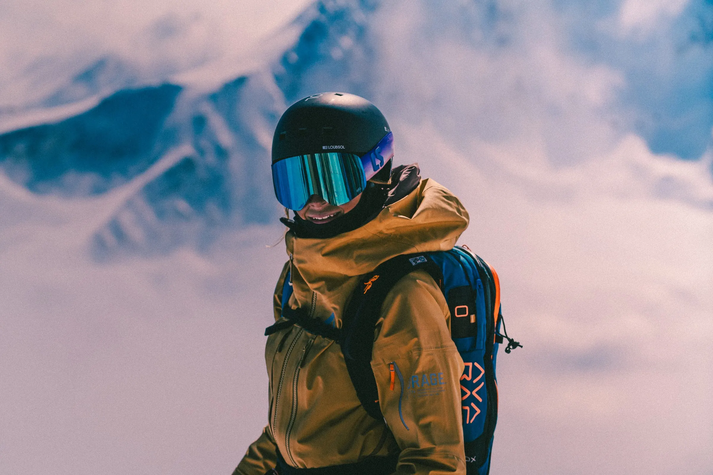 Female ski tourer in a yellow Orage MTN-X jacket with a rucksack above the clouds