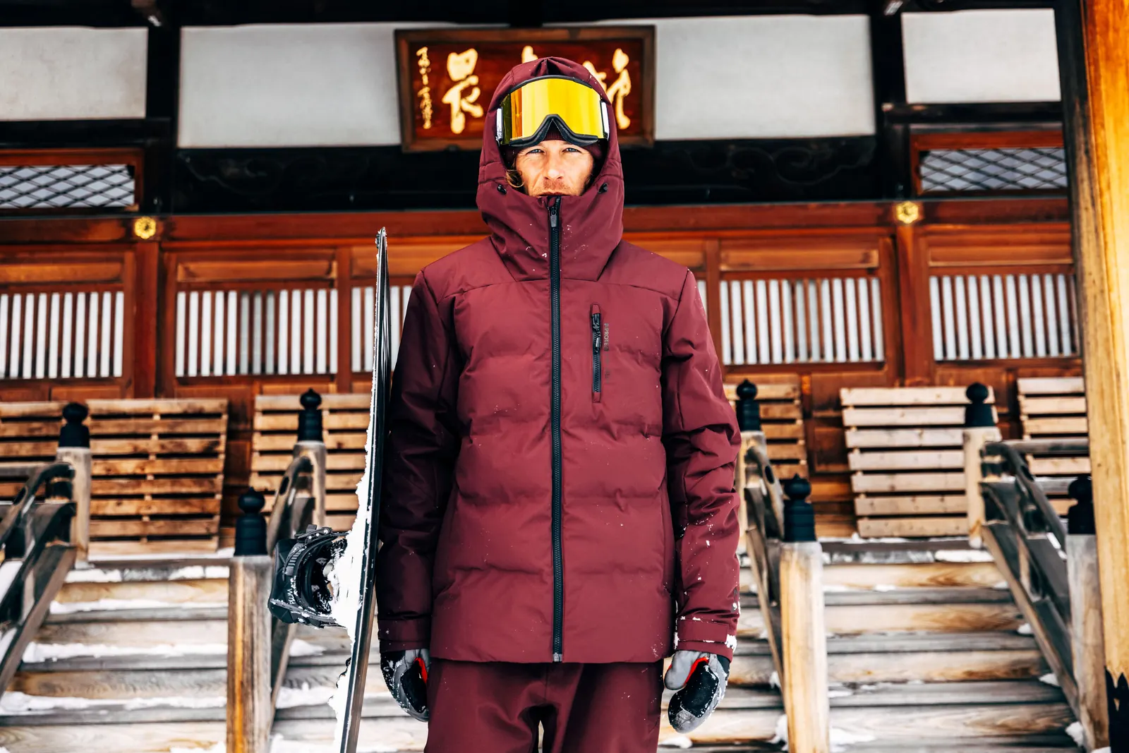 Mann in bordeauxroter Protest-Skijacke mit Skibrille