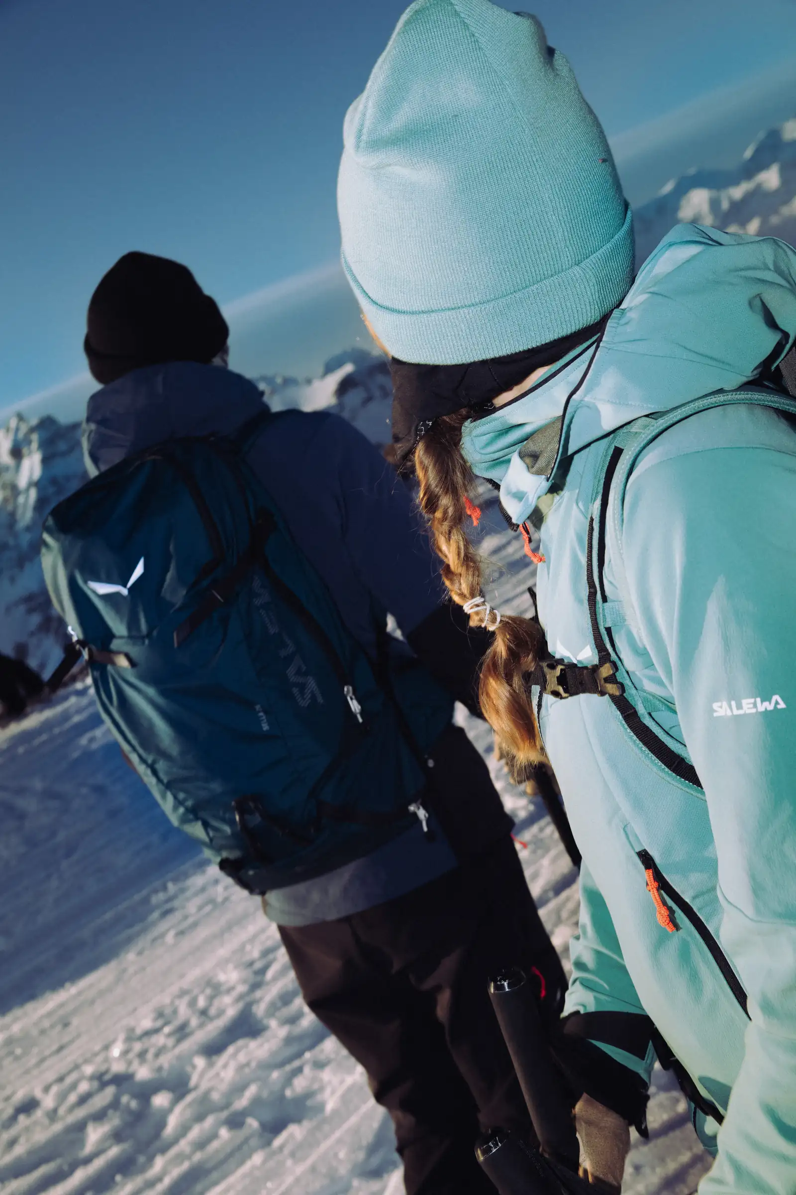 Zwei Skitourengeher:innen beim Anlegen der Ski im Sonnenaufgang