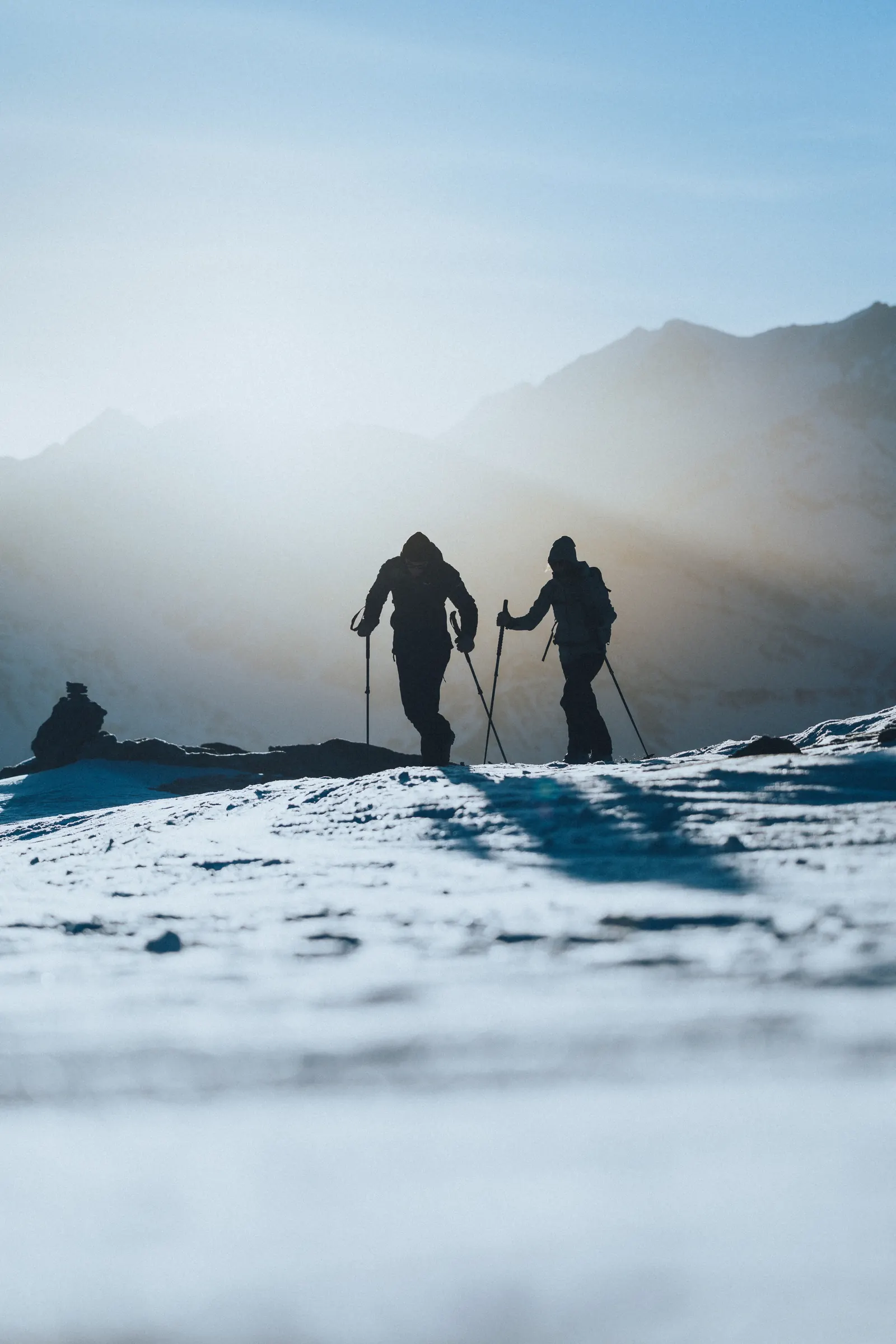 Zwei Skitourengeher:innen im Aufstieg vor winterlicher Bergkulisse