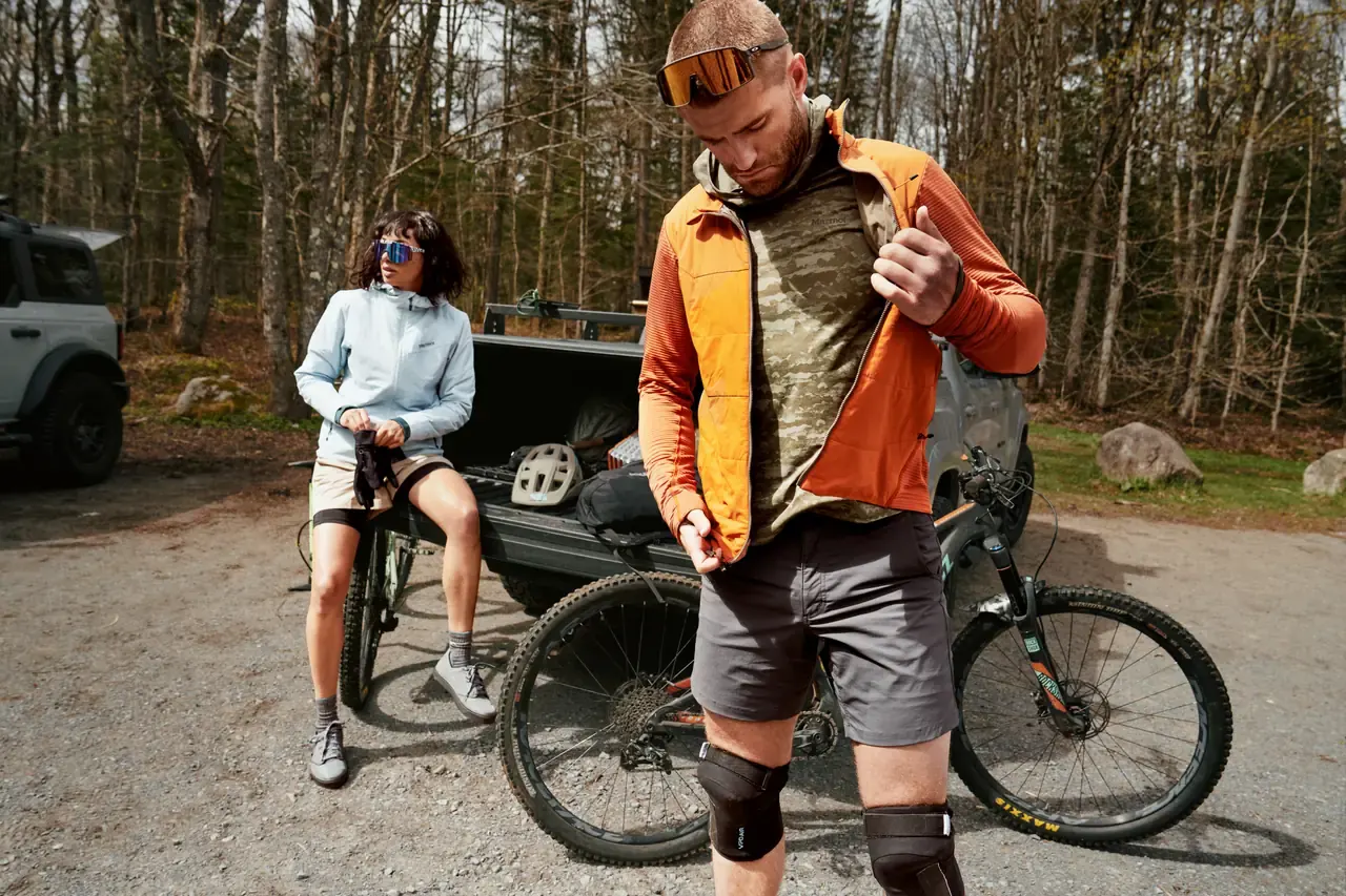 Mountainbiker zieht vor der Tour eine orangefarbene Marmot-Jacke an