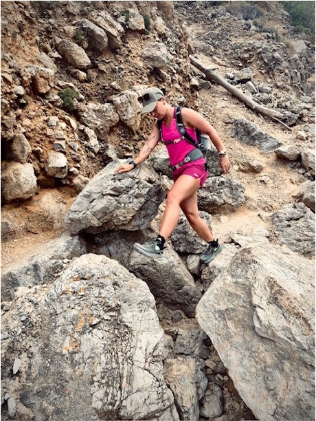 Ines steigt in Wanderausrüstung über große Felsblöcke auf einem Trail auf Mallorca