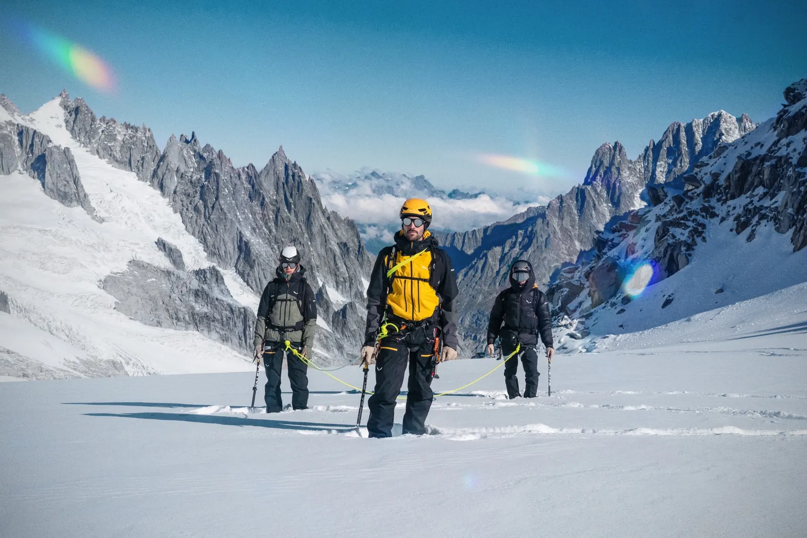 Drei Bergsteiger in Salewa-Ausrüstung am Seil auf einem Gletscher vor Felsgipfeln