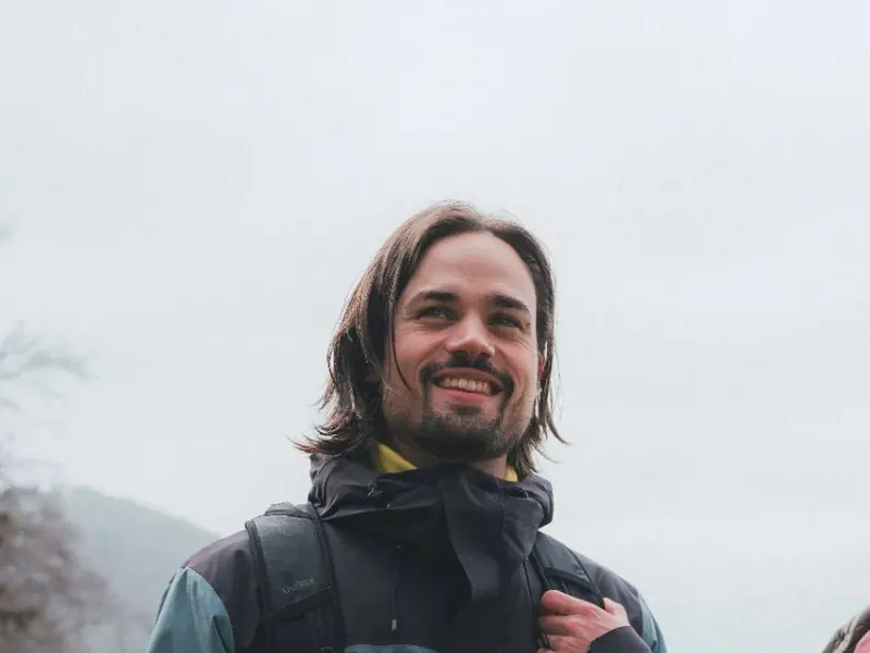 Wanderer in Schöffel-Jacke mit Rucksack vor nebligen Bergen