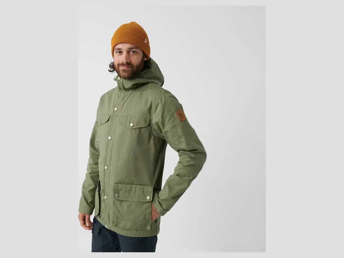 Mann in grüner Fjällräven Greenland Jacket mit orangefarbener Mütze