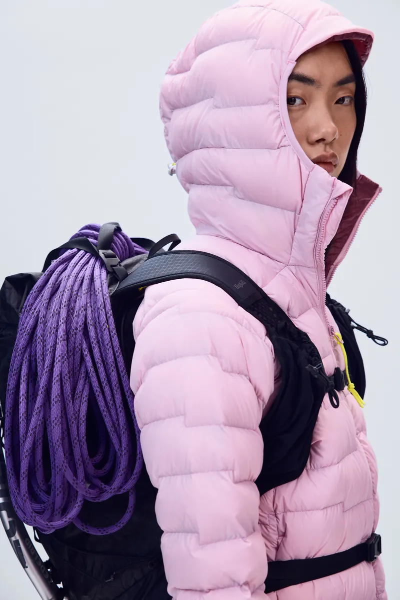 Woman in a pink Haglöfs ROC Flash Down Hood with a climbing rope on her backpack