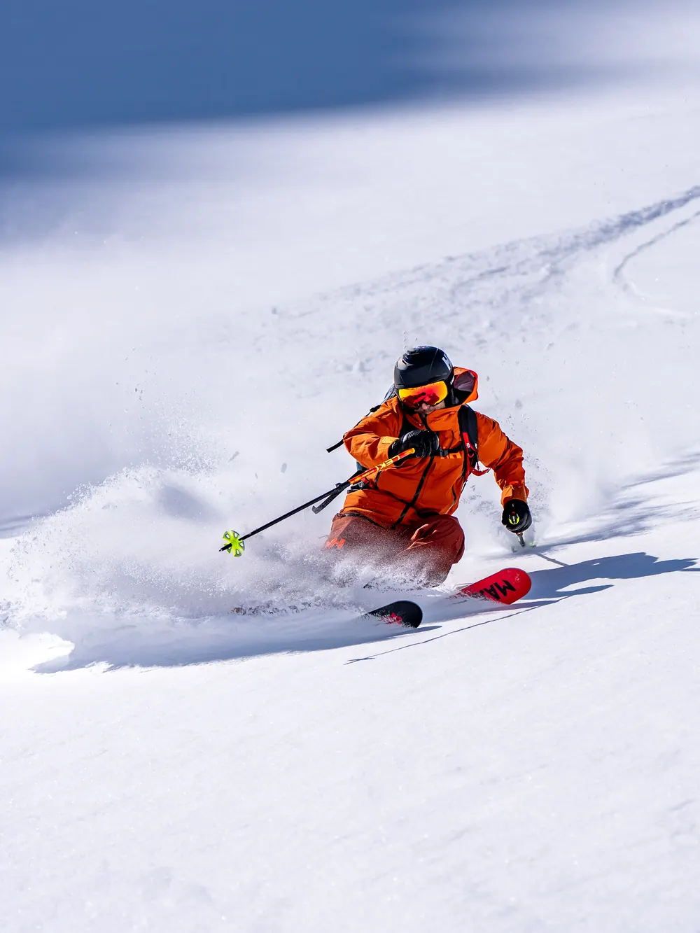 Freerider in orange Helly Hansen ski wear skiing through powder