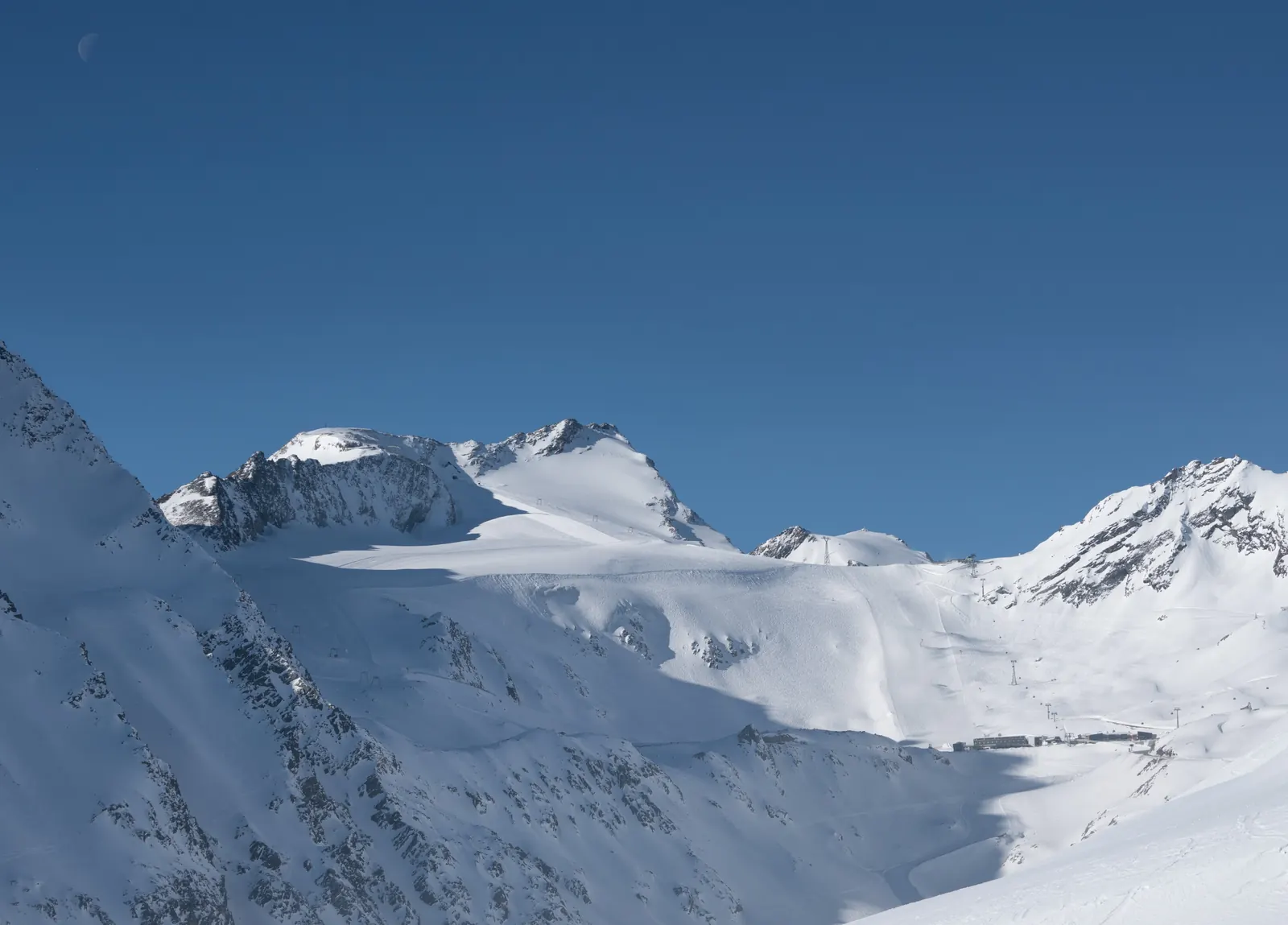 Verschneiter Rettenbachgletscher mit Pisten und Gipfeln unter blauem Himmel