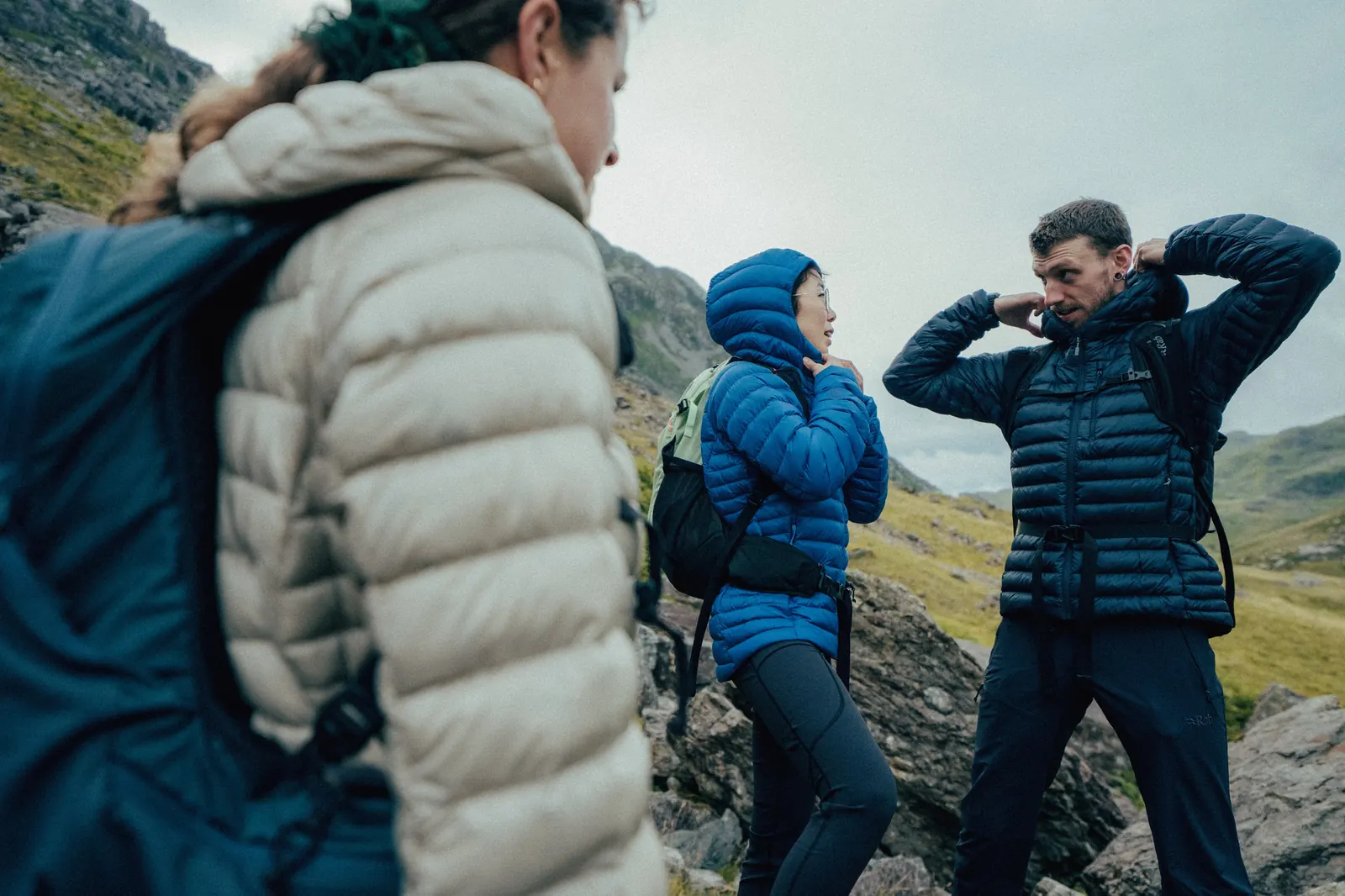 Three people wearing the Rab Microlight Alpine in beige, blue and dark blue