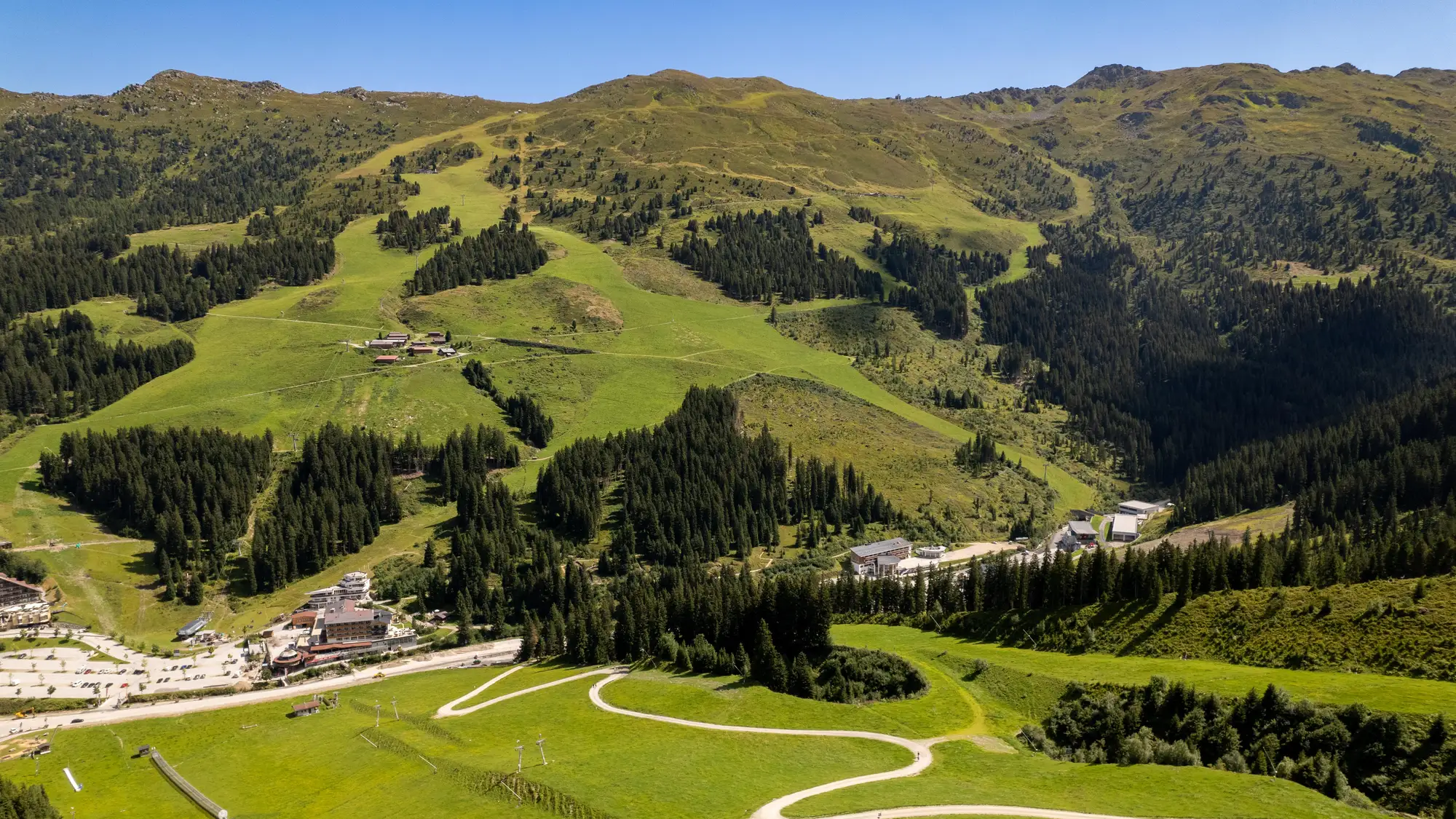 Blick auf Hochfügen mit Gebäuden, Wiesen, Wegen und bewaldeten Berghängen