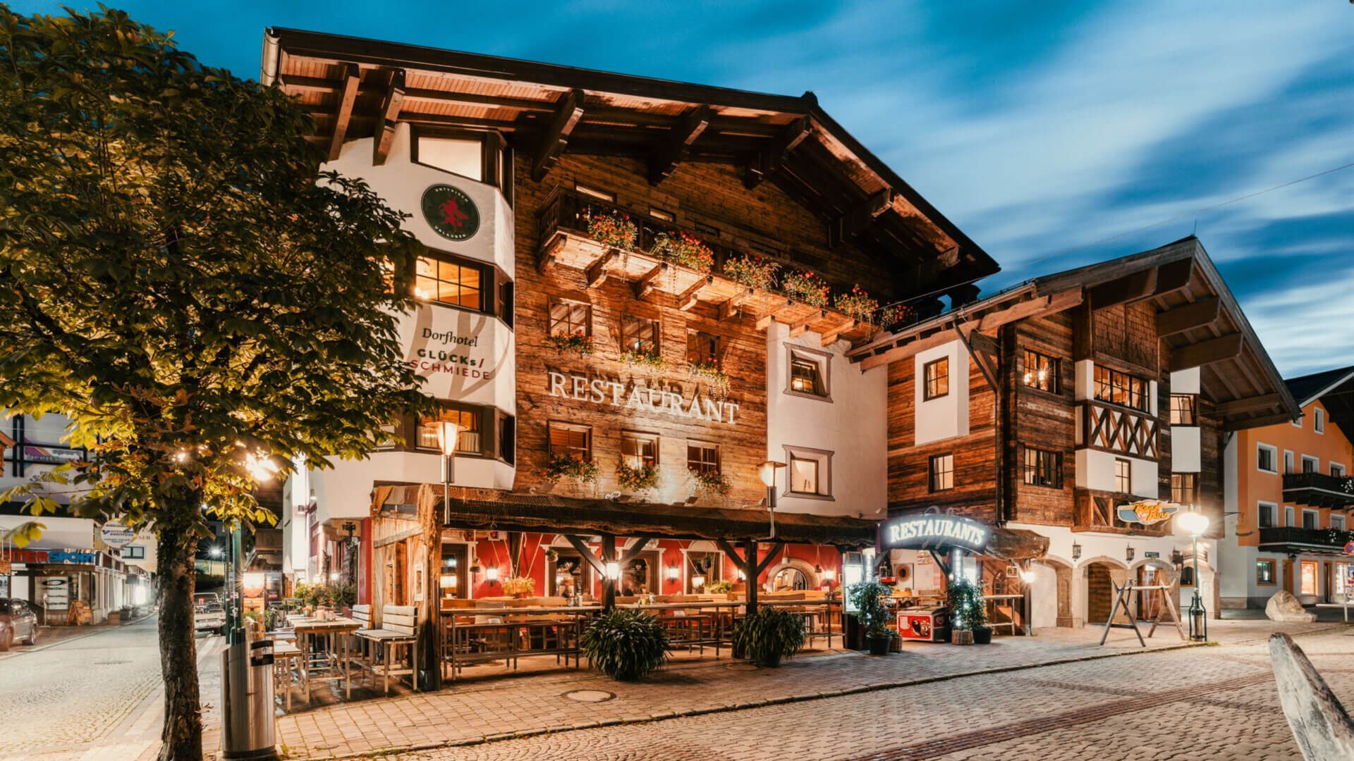 Fassade der Glücksschmiede in Hinterglemm mit Holzbalkonen und Restaurantterrasse