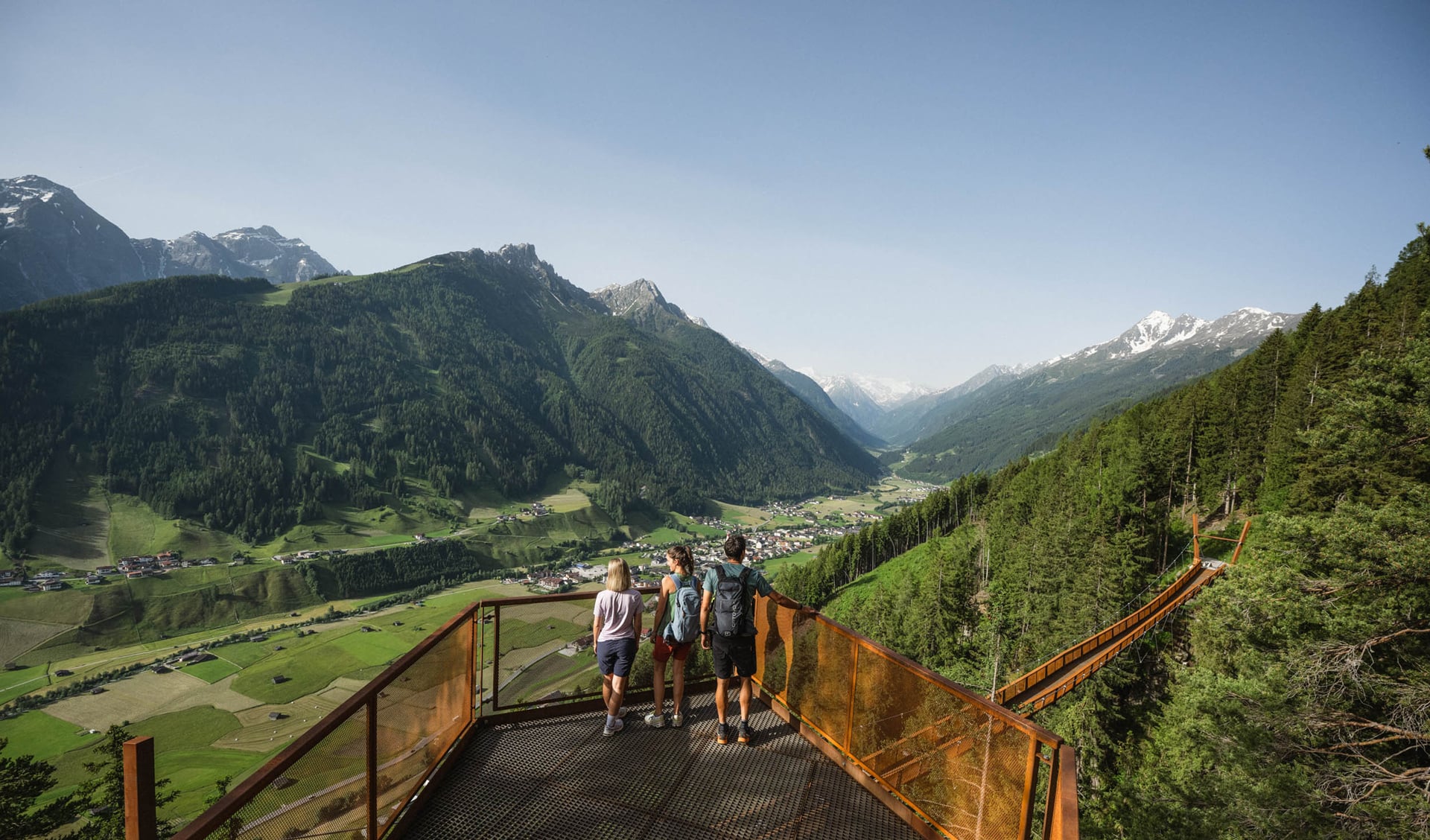Wandernde auf einer Aussichtsplattform über dem grünen Stubaital