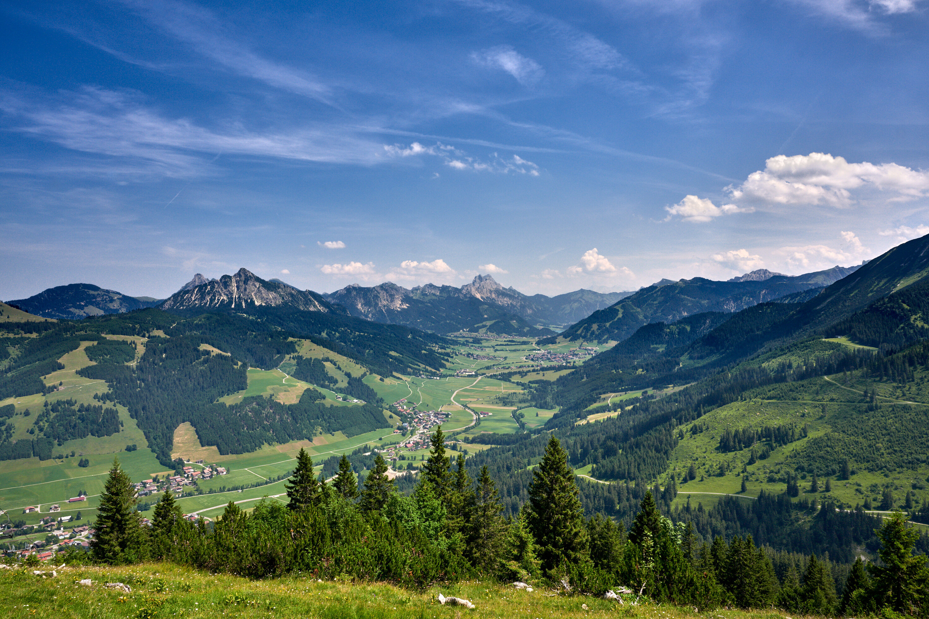 Blick über das Tannheimer Tal mit Dörfern, Wiesen und Bergketten