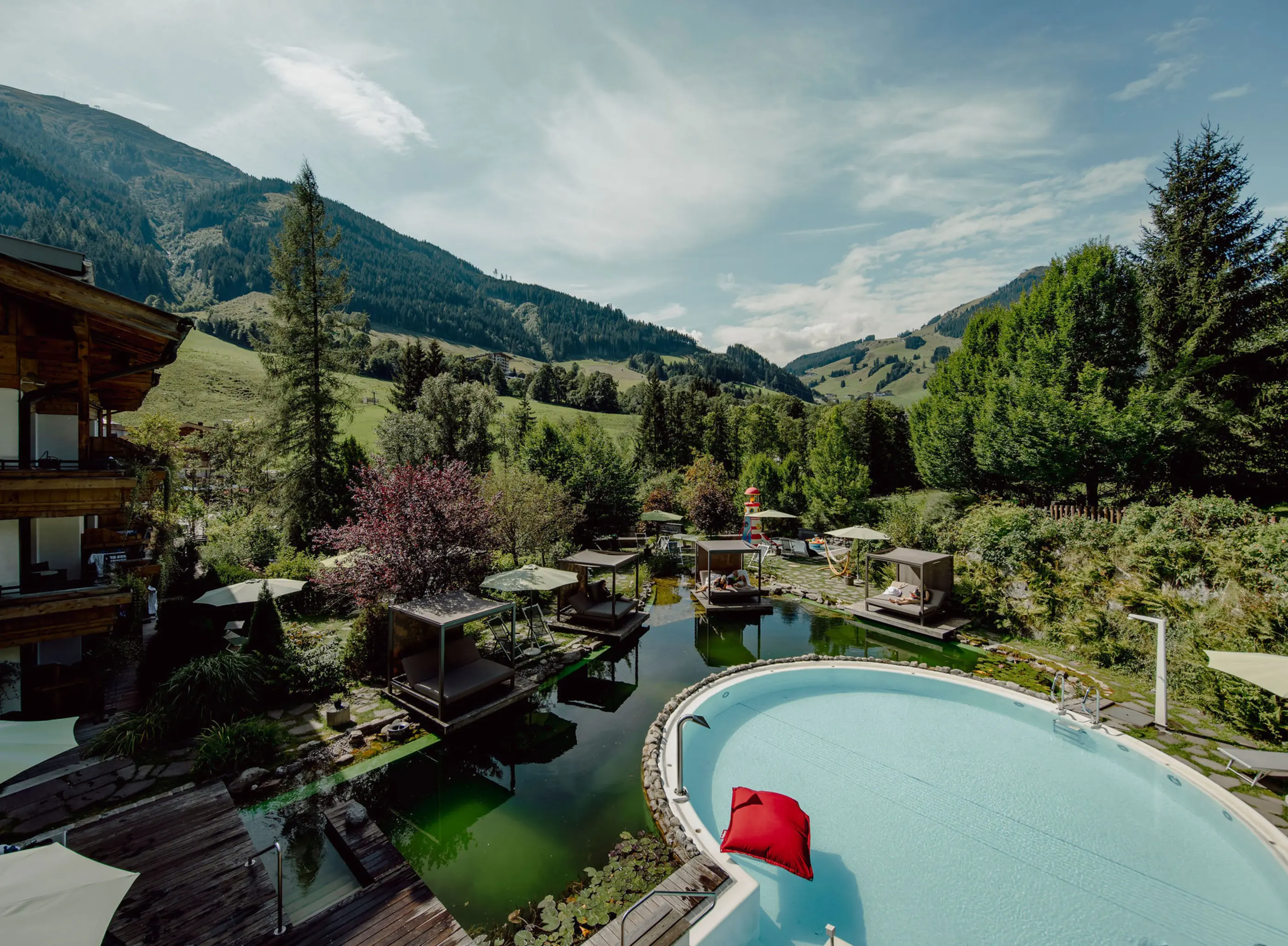 Garten mit Pool und Schwimmteich bei The RESI Apartments in Hinterglemm vor Berghängen
