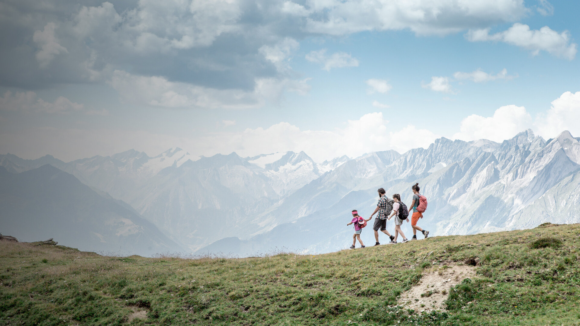 Wandernde auf einem grünen Bergrücken im Großglockner Resort Kals-Matrei