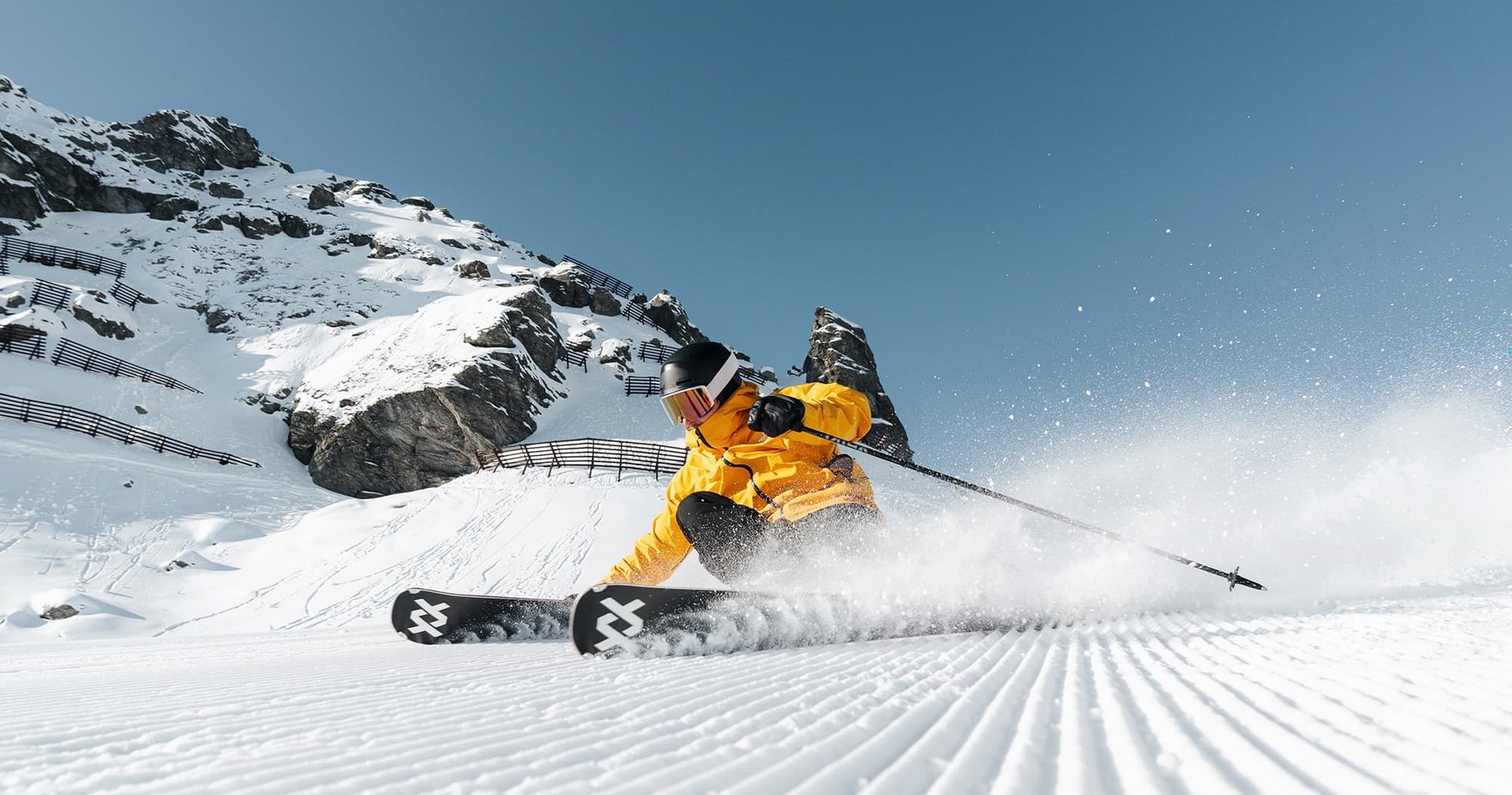 Skifahrende Person in gelber Jacke auf einer präparierten Piste in Hochfügen