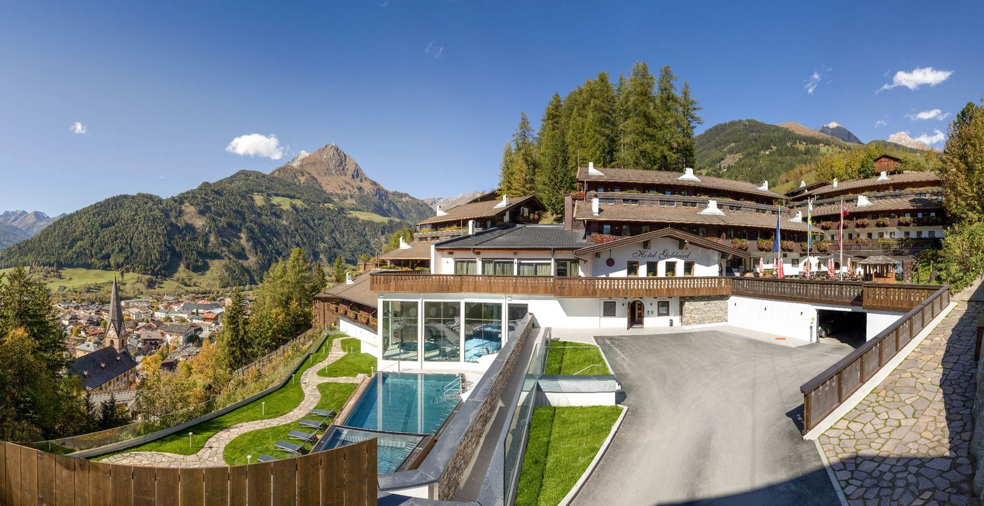 Hotel Goldried am Hang oberhalb von Matrei mit Balkonen und Bergen im Hintergrund