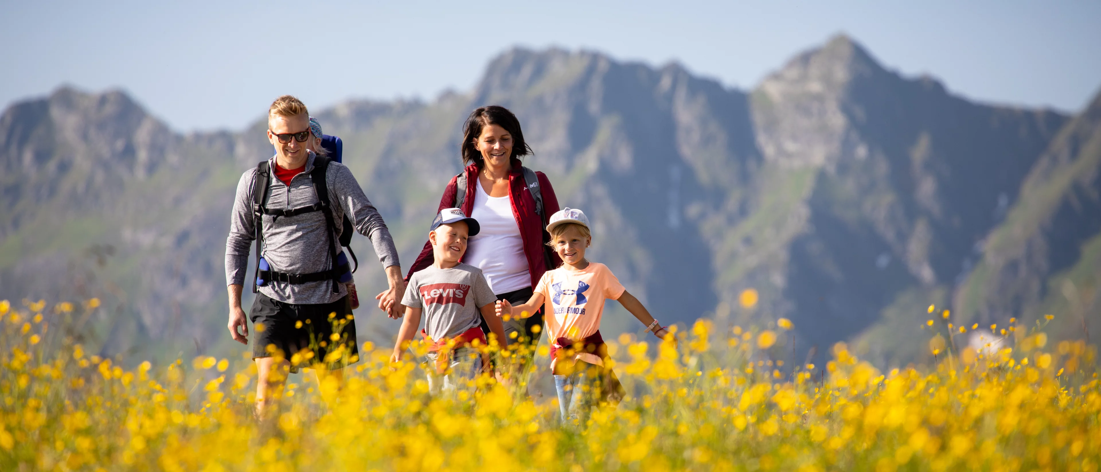 Familie beim Wandern durch eine Blumenwiese am Wiedersberger Horn